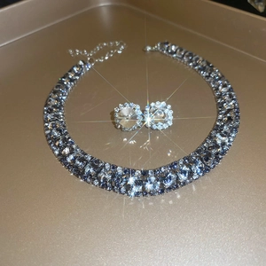 Detail of square zircon necklace and earring set with starburst effects on a gold tray