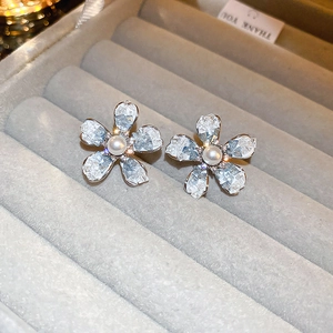 Macro shot of silver flower earrings with ice crystal petals and central faux pearl