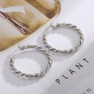 Close-up of silver twisted rope hoop earrings made of polished stainless steel