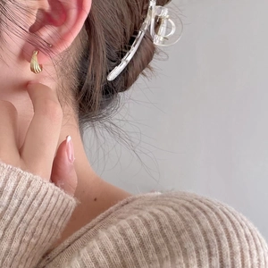 Detail view of gold textured geometric hoop earring on model showing vertical stripes