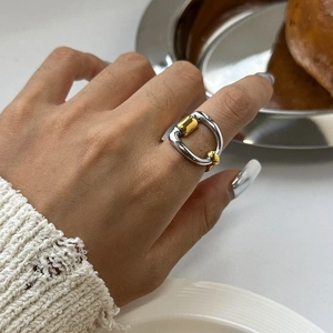 Close-up of dual-tone stirrup ring in gold and silver finish on hand with polished detail