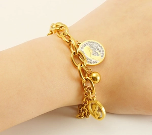 Macro detail of 18K gold-plated bracelet featuring rhinestone pavé and hollow pendants