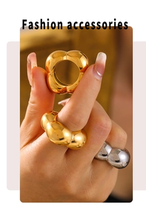 Close-up of puffy gold and silver chunky dome rings worn on fingers in soft light