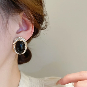 Close-up of vintage oval stud earrings with black center stone and sparkling rhinestones