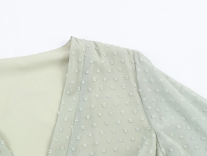 Détail du tissu en mousseline vert clair avec pois suisses texturés sur le col et l'épaule