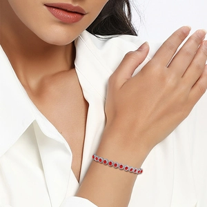 Close-up of a silver tennis bracelet featuring red round gemstones and zircon accents