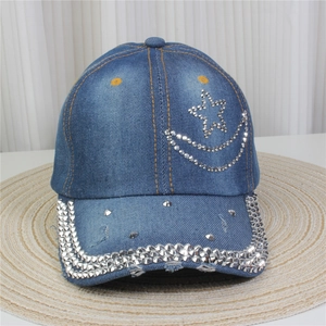 Détails des motifs de lune et d'étoiles en strass sur la casquette en denim bleu délavé