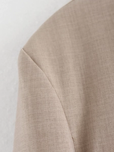 Close-up of structured shoulder seam and camel woven fabric texture on a women's jacket