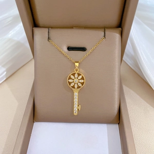 Detail of starburst key necklace with sparkling zircons in a beige jewelry box