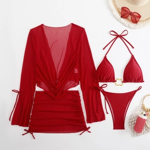 Flat lay of red three-piece bikini set with sheer mesh cover-up and beach accessories