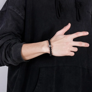 Detail of matte black onyx bead bracelet with metal skull charm on a male wrist