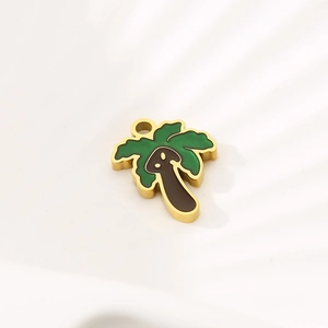Detail of a tropical palm tree pendant with green enamel and gold finish on white surface
