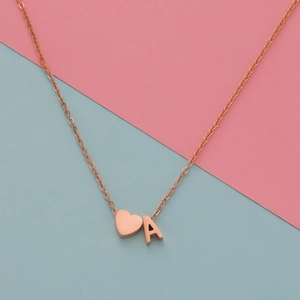 Detail of rose gold heart pendant with letter A on a pink and blue background