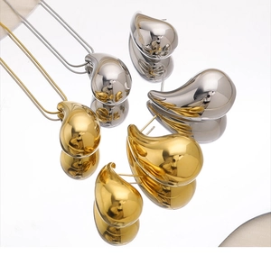 Macro shot of polished teardrop necklace and earrings set in gold and silver plating