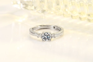Macro view of silver four-prong moissanite ring with milgrain details and side stones