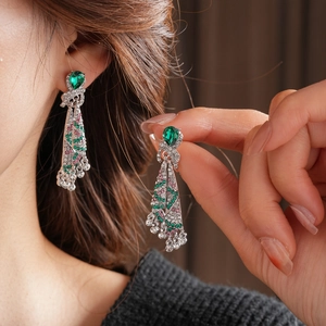 Close-up of vintage drop earrings with emerald green crystals and sparkling tassels