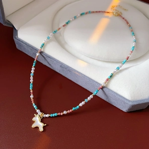Detailed close-up of beaded necklace with mother of pearl unicorn pendant in velvet box
