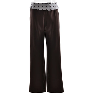 Detail view of high-waist brown wide-leg trousers with grey polka dot waistband folding