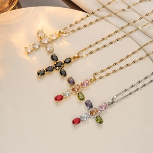 Macro shot of multiple gold and silver cross necklaces with colorful zircon stones on silk
