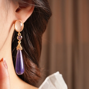 Gros plan de boucles d'oreilles vintage dorées avec gouttes en résine violette