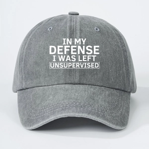 Detailed close-up of IN MY DEFENSE text printed on a vintage washed grey cotton baseball cap