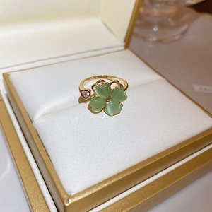 Detail of green cat-eye clover ring with heart zircon in a premium golden jewelry box