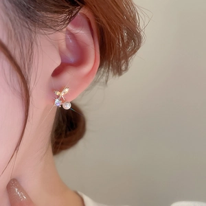 Nahaufnahme eleganter Kirschohrringe mit Zirkonia und Perle auf vergoldetem Metall am Ohr