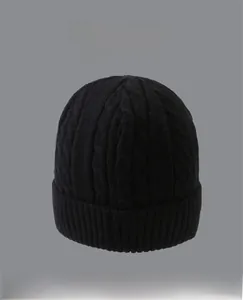 Detailed close-up of a black cable-knit beanie featuring a thick ribbed fold-over cuff