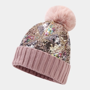 Détail du bonnet en maille rose avec paillettes colorées et pompon en fausse fourrure