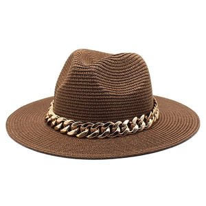 Detailed macro view of brown straw fedora with decorative gold metal chain link