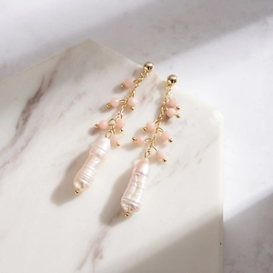 Detail of baroque pearl earrings with pink beads on a white marble background