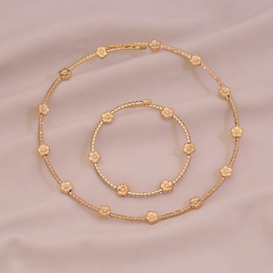 Elegant gold necklace and bracelet set featuring delicate floral motifs and small crystals