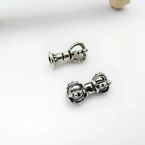 Detailed macro view of Tibetan silver vajra bell charms for DIY Buddhist jewelry making