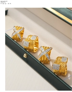 Close-up of four gold plated titanium rings with diamonds in a luxury green jewelry box