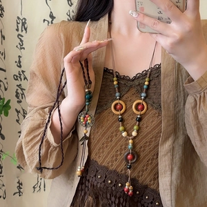 Detail of ethnic style long necklace with ceramic beads and wooden ring on lace fabric