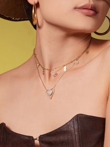 Detail of layered gold heart necklace featuring tree of life and infinity pendants