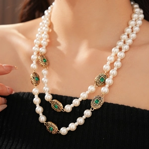 Dettaglio della collana di perle vintage a doppio strato con pietre verdi e oro