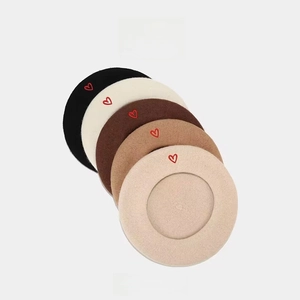 Stack of wool berets in five colors featuring delicate red heart embroidery on the side