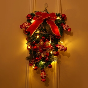 Detailansicht eines festlichen Weihnachts-Türhängers mit warmen LED-Lichtern und roter Schleife