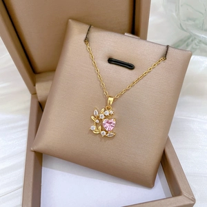 Close-up of golden necklace with pink heart gem and leaf zircon in a jewelry box