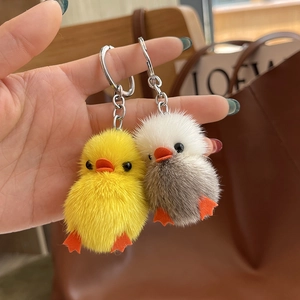 Close-up of yellow and grey plush duck keychains with soft faux fur and metal rings