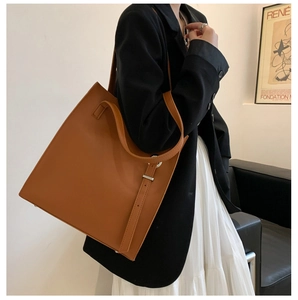 Minimalist brown leather tote bag worn by a model in a high-fashion editorial setting