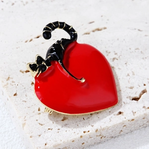 Close-up of heart-shaped cat brooch with red enamel and gold-plated alloy details