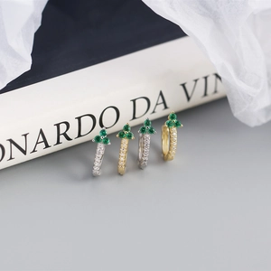 Detailed macro of gold and silver geometric floral earrings with green crystals