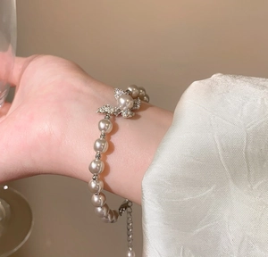 Dettaglio ravvicinato di un elegante bracciale di perle con ciondolo a farfalla al polso