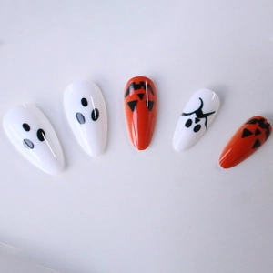 Halloween almond press-on nails with orange pumpkins and white ghosts on a light background