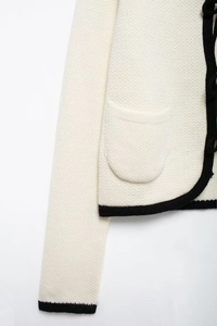 Détail d'un cardigan blanc en maille avec bordure noire et poche avant pratique