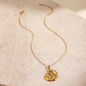Goldene Spiralhalskette aus Edelstahl auf minimalistischem beigem Steinhintergrund aus Edelstahl