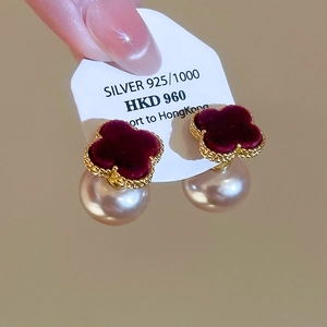 Macro shot of 925 silver earrings with velvet clover motifs and lustrous pearl drops