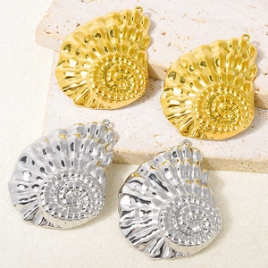 Macro view of gold and silver shell pendants on a natural beige travertine stone